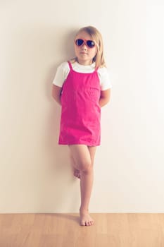 Little girl posing in front of a wall. Studio shot.