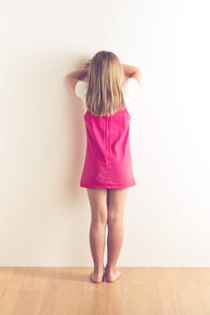 portrait of sad little girl standing near wall. studio shot
