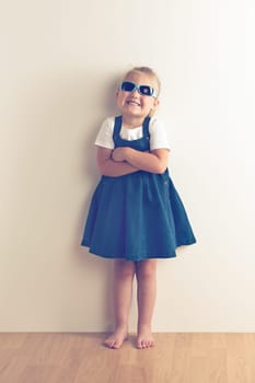 Little girl posing in front of a wall. Studio shot.