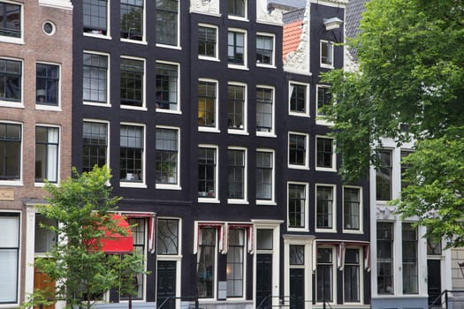 Close up view of the narrow houses along the canals in Amsterdam. (The Netherlands). All potential trademarks are removed.