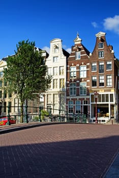 Bridge and the narrow houses along the canals in Amsterdam. (The Netherlands). All potential trademarks are removed.