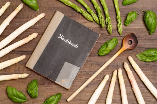 Cookbook with cooking spoon and white and green asparagus