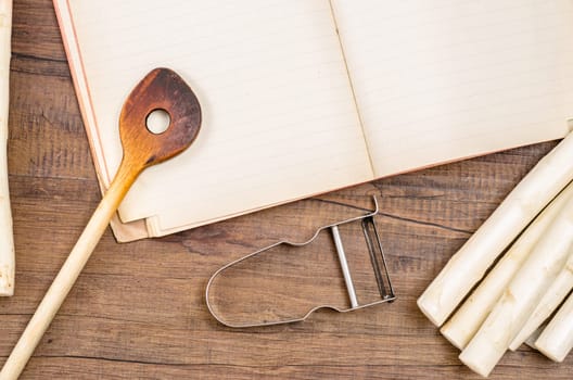 Cooking spoon and book,peeler and white asparagus