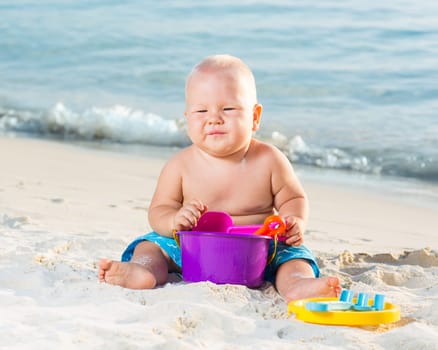 Cute baby on the tropical beach playing toys