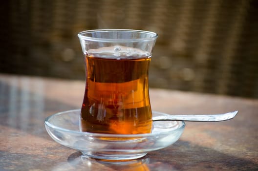 Turkish tea in glass and spoon on a table.