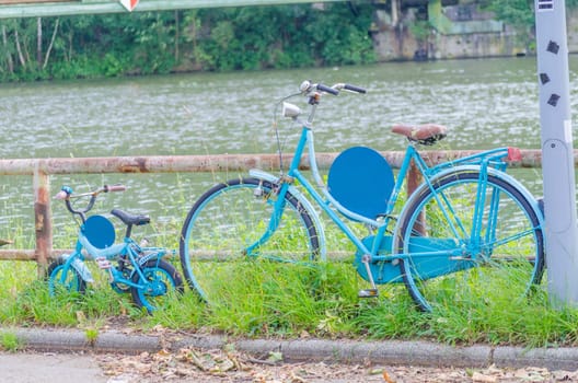 A large women's bike and a small blue children's bike on the shore.