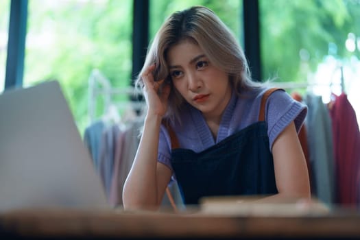 Starting small business entrepreneur of independent Asian woman showing her face worried about the sales of her business not reaching the target set. SME concepts.