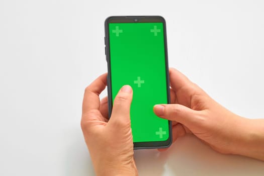 Elderly woman hands holding smartphone with green screen. The chromakey. Green screen