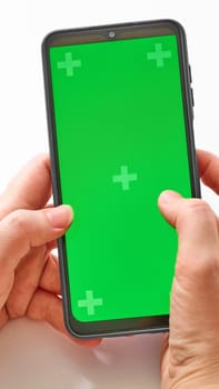 Elderly woman hands holding smartphone with green screen. The chromakey. Green screen