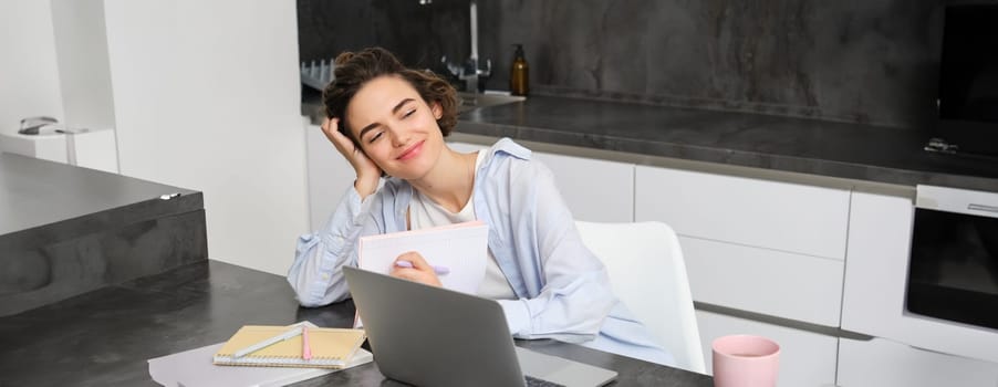 Portrait of 25 years woman, studies online, watches course in internet, works on laptop from her home.