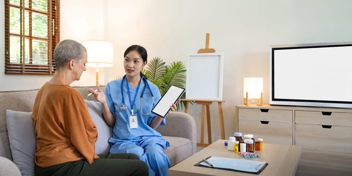 Caregiver and senior woman serious and shocked by the results of the health examination going through medical record on digital tablet during home visit.