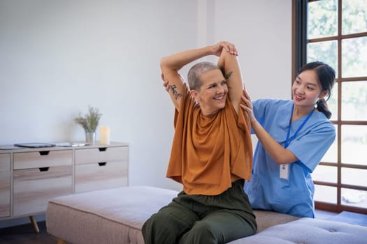 Senior elderly famale or patient sitting on sofa in living room the caregiver is checking his body in home.