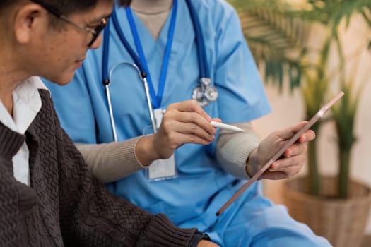 Asian nurse showing health checkup report to older and giving advice. Home nursing and healthcare caregiver concept.