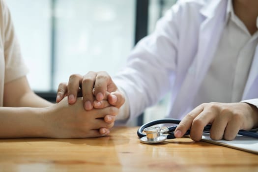 Kind doctor offering a loving gesture to a sick person during a health crisis. Support, trust and hospital care with a doctor and patient holding hands, sharing bad news of a cancer diagnosis.