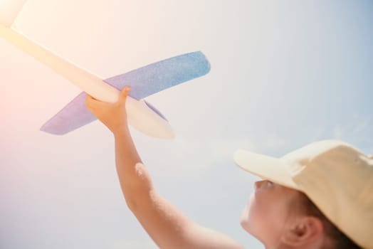 Kid playing with toy airplane. Children dream of travel by plane. Happy child girl has fun in summer vacation by sea and mountains. Outdoors activities at background of blue sky. Lifestyle moment