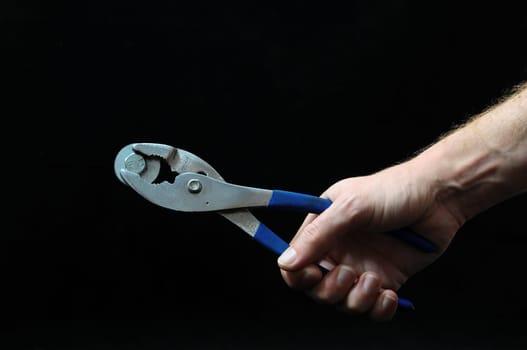 Pliers and a Hand on a Black Background