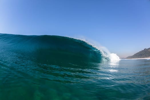 Ocean sea wave vertical crashing hollow tubing water power on shallow beach reefs sandbars, a swimming surfer action water photo