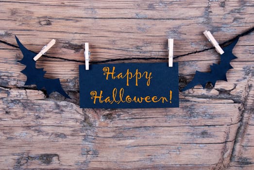 Orange Happy Halloween on a Black Label on a Line with Bats on Wood