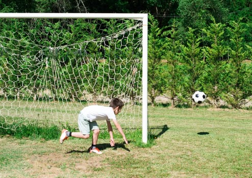Child playing football in a stadium. Trees on the background