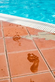 Footprints of bare feet to swimming pool. Water footprints