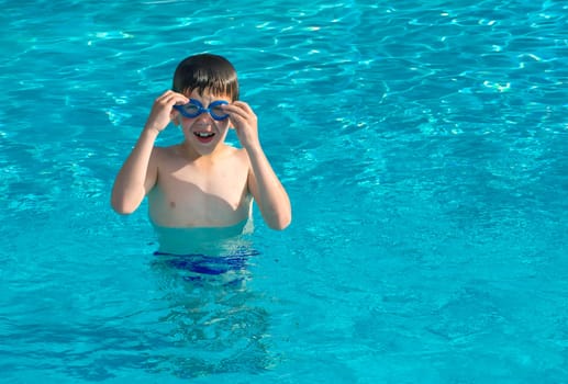 Child in swiming pool. Blue glasses
