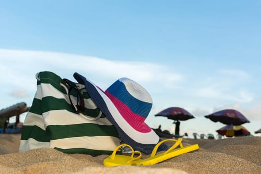 Summer concept of straw hat, bag, sunglasses and flip flops on a tropical beach.