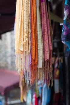 bunch of colorful shawls hanging in a market stand
