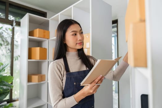 A young woman efficiently organizes inventory and manages packages in a bright workspace, showcasing her attention to detail.