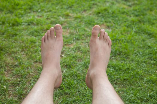 Bare feet laying on green grass background