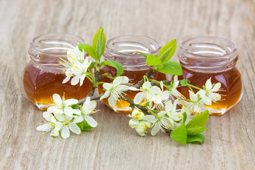 Honey in jars and flowers on wooden background