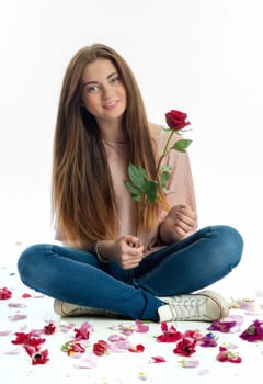 Girl sits amid rose petals