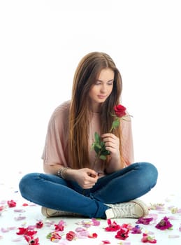 Girl sits amid rose petals