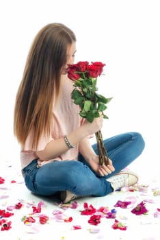 Girl sits amid rose petals