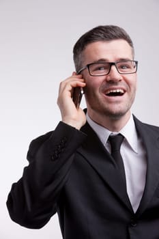 an elegant dressed man with a pair of eyeglasses happy and talking his mobile phone