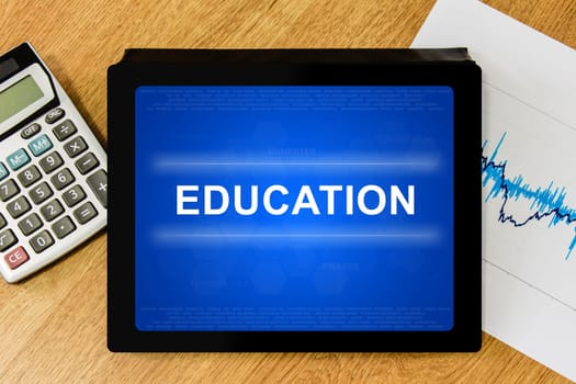 Education word on digital tablet with calculator and financial graph