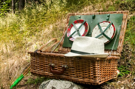 Vintage wicker picnic suitcase on mountain meadow background