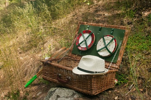 Vintage wicker picnic suitcase on mountain meadow background