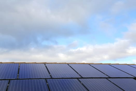 Solar panels on a house roof, with sky background
