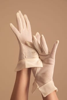 A woman's hands and forearms are shown as she models a vintage pair of formal white mesh gloves with unique cuff. She is using one hand to pull on the other glove.