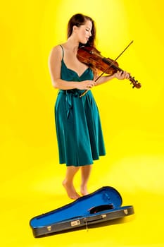 A beautiful female violinist over a yellow background.