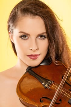 A beautiful female violinist over a yellow background.