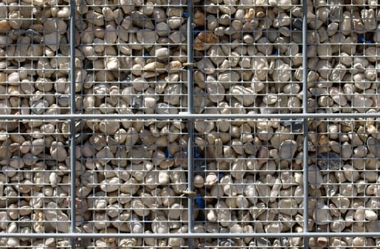 The photograph of a steel grid with pebbles usable as a fence.