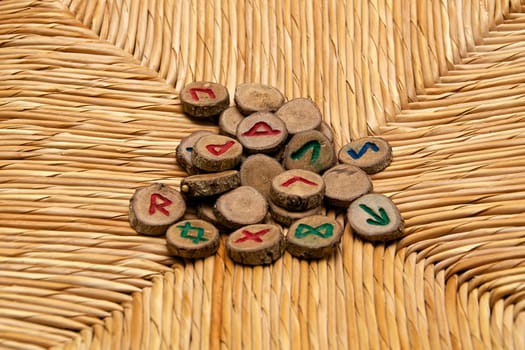 A pile of germanic runes, an ancient alphabet known as the futhark are on a woven rattan surface..Note