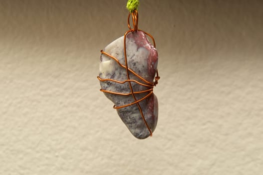 A blue turquoise and white semi polished stone is wrapped in copper wire and suspended. .Note