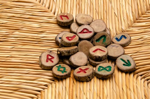 A pile of germanic runes, an ancient alphabet known as the futhark are on a woven rattan surface..Note