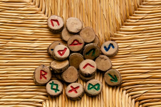 Looking own on a pile of germanic runes, an ancient alphabet known as the futhark on a woven rattan surface..Note