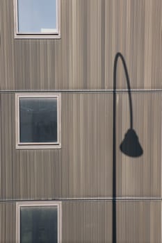 The photograph of a facade with windows and the shadow of a lantern.
