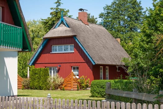 red painted wooden thatched-roof house with garden