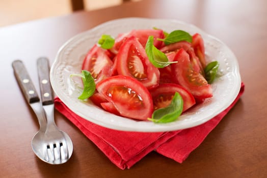 fresh tomato slice with basil leaves in a bowl