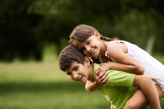 People in love with happy little girl and boy running piggyback in city park. Copy space